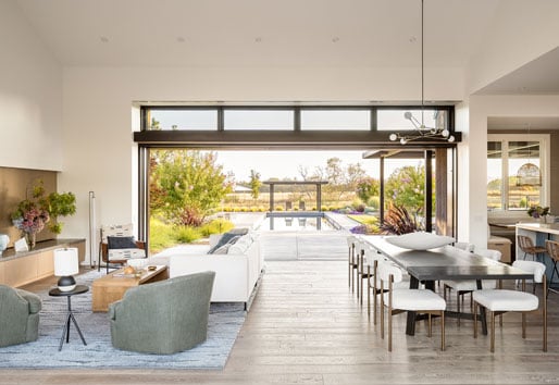 A living room with one wall that completely opens up to the pool area outside.
