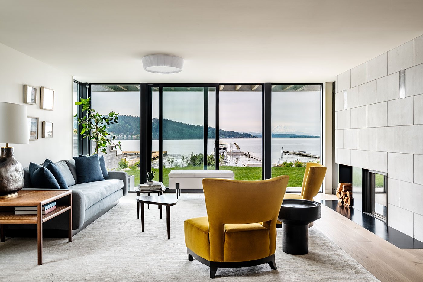 A living room with floor-to-ceiling glass showcasing lake views and a fireplace.
