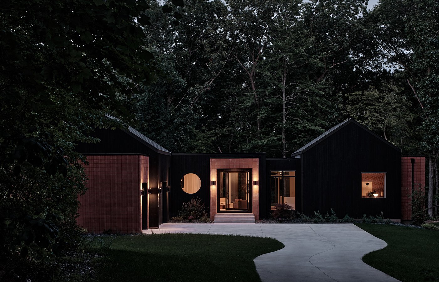 A home lit up at dusk with an Andersen® A-Series Specialty Window in the shape of a circle.