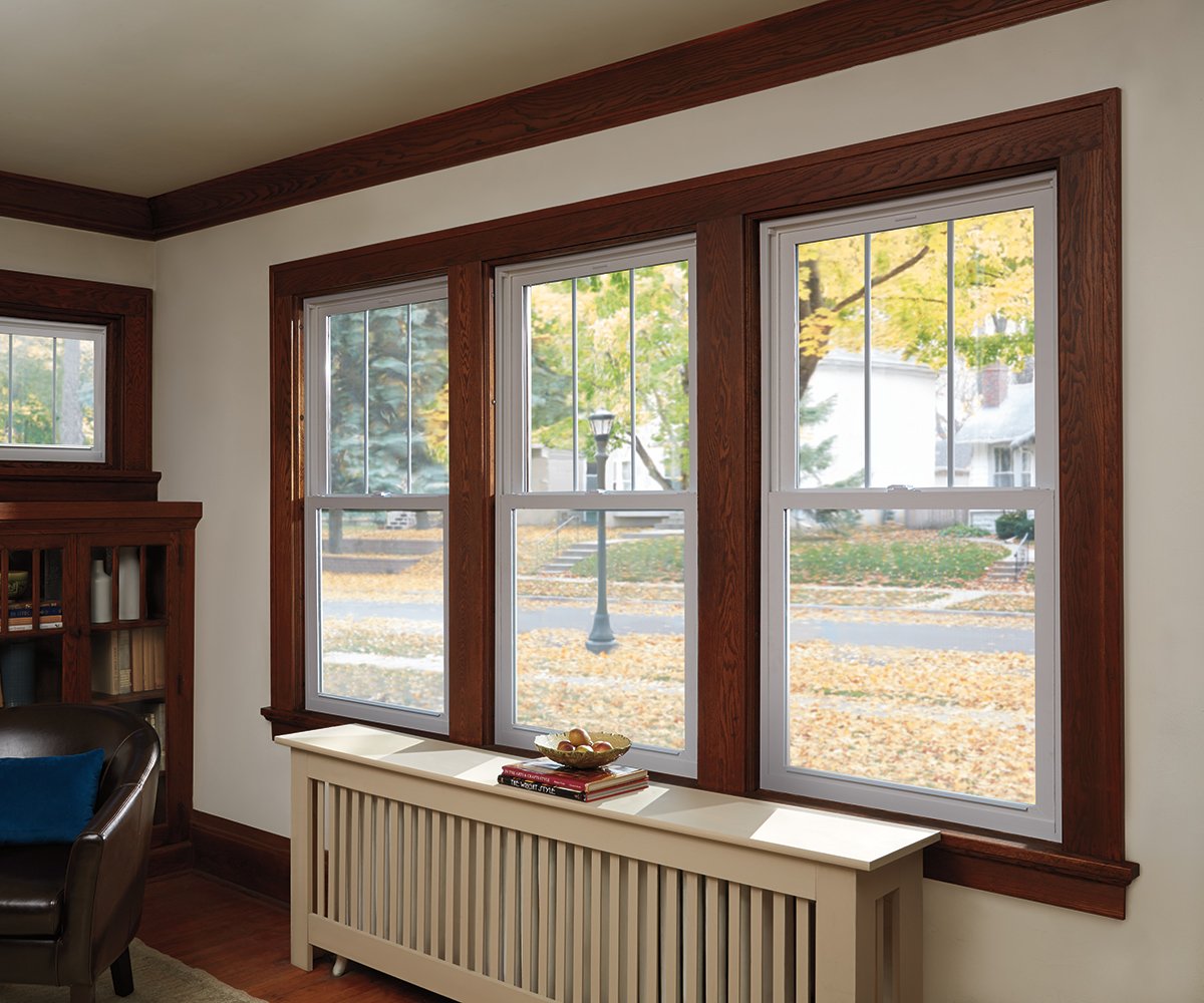 A living room with vinyl replacement windows on the left and with Andersen Woodwright Double-Hung Windows on the right.