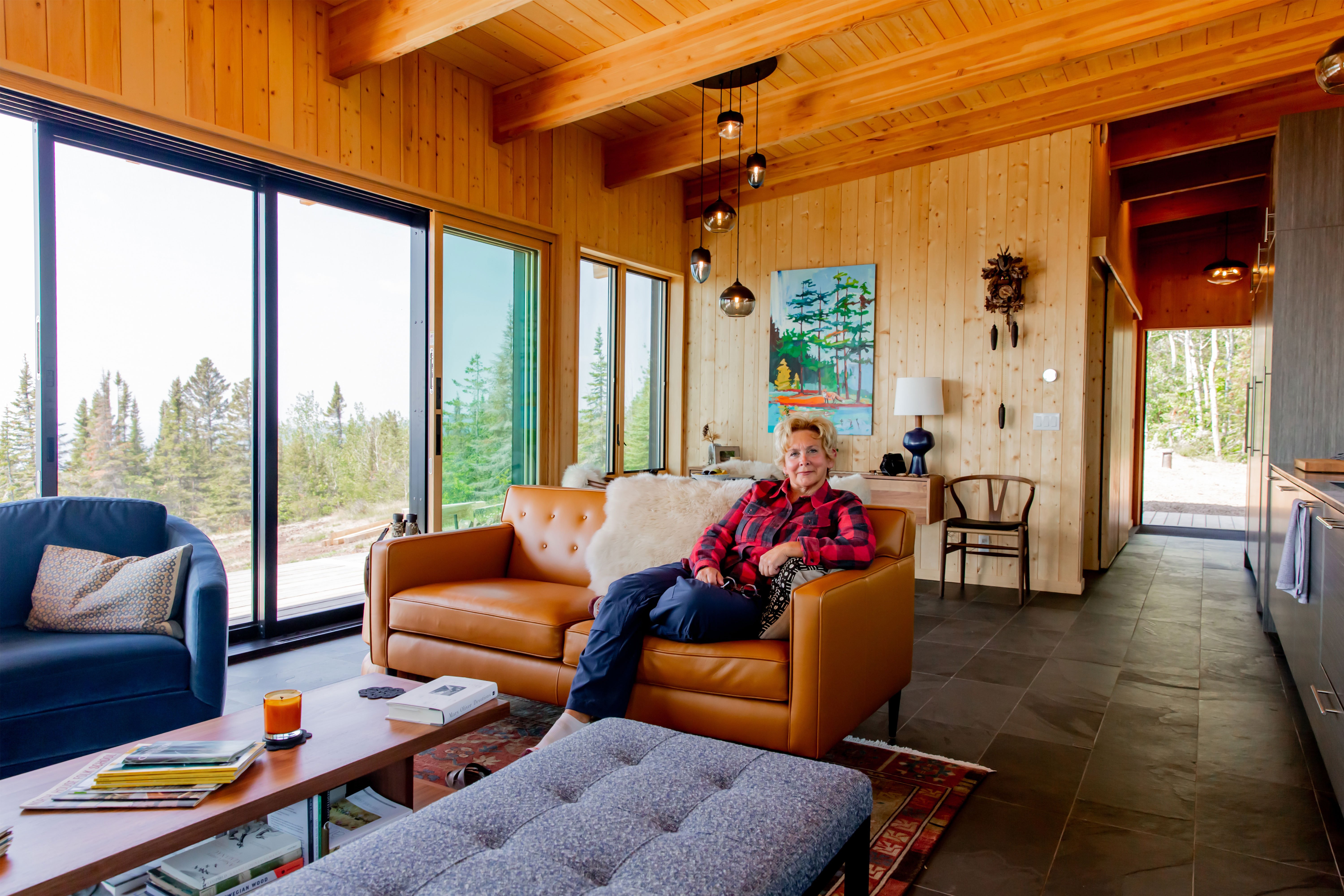 Krissie Mason sits on a leather couch in an open concept space while behind her sliding glass doors fill an entire wall.