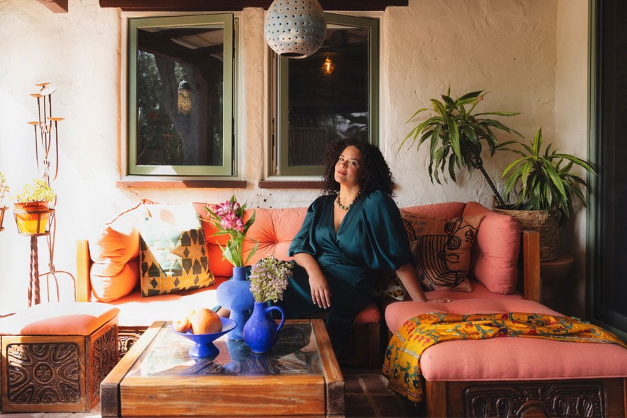 Justina Blakeney sits on an outdoor sofa underneath a set of two E-Series Casement Windows.