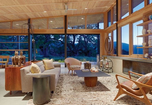 A living room with Liftslide Doors that fill an entire wall and abuts a wall filled with casement windows
