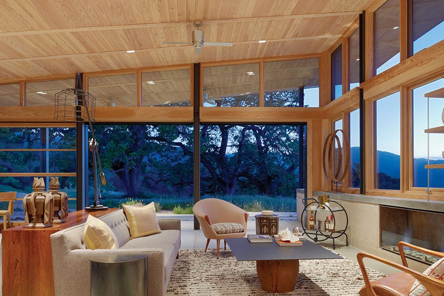 A living room with Liftslide Doors that fill an entire wall and abuts a wall filled with casement windows