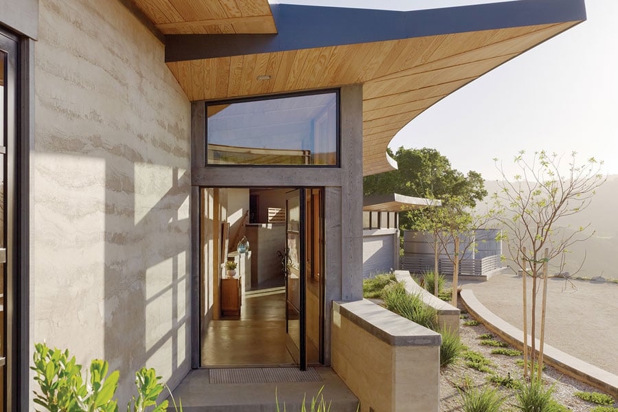 Two views of the home’s entrance, which features a Pivot Door with a clerestory window above.