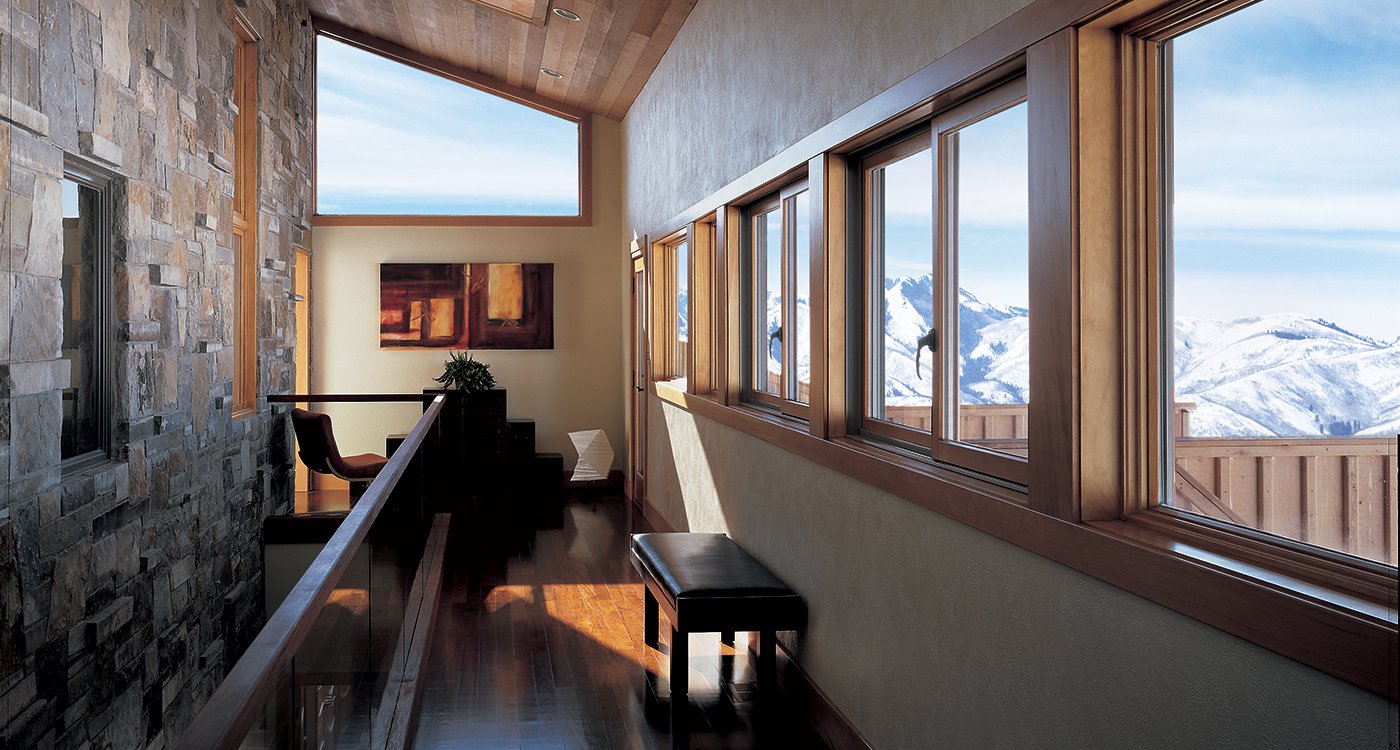 A hallway lined with Andersen® 400 Series Gliding Windows that overlook a dramatic mountain landscape.
