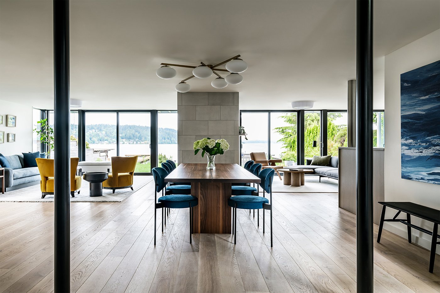 A dining room space in an open concept layout with floor-to-ceiling glass in the form of sliding glass doors and windows.
